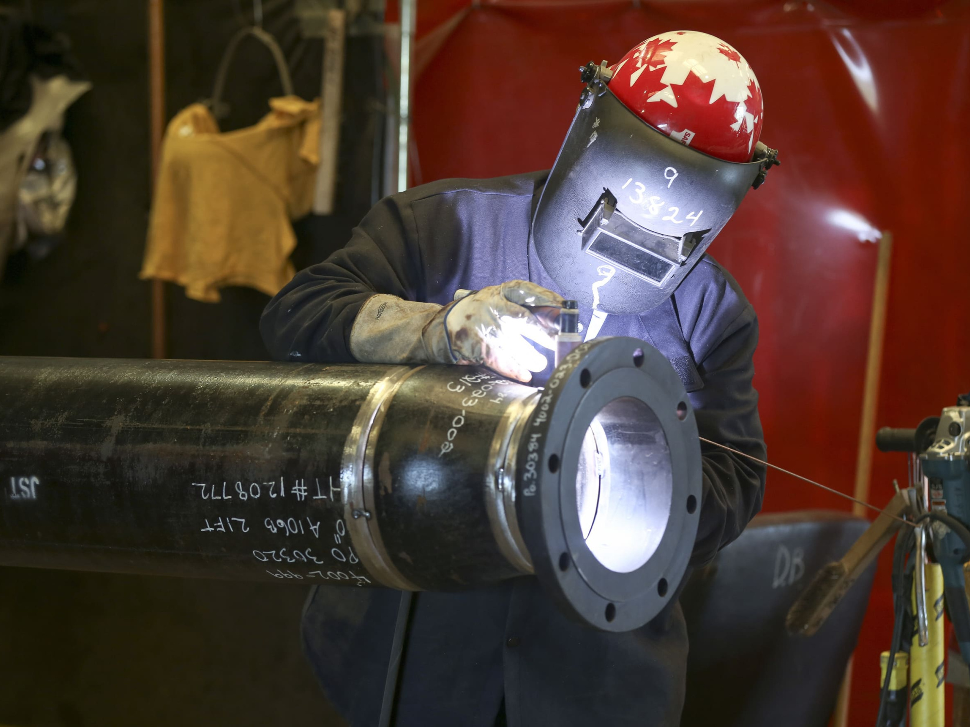 a trades person welding a pipe with safety gear on