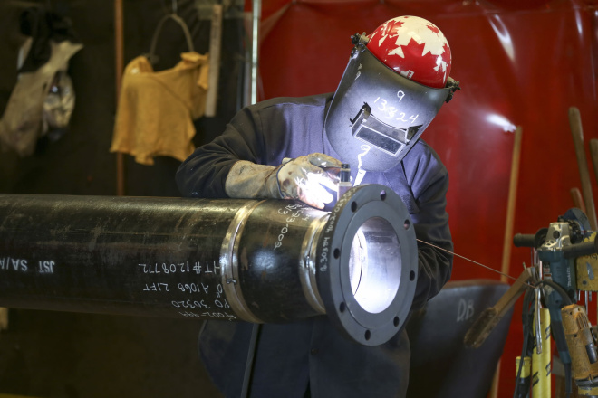 a trades person welding a pipe with safety gear on
